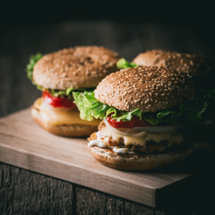 Fresh tasty grilled beef burgers with cheese wood background.