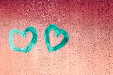 Aquamarine hearts drawn with a finger on wet glass