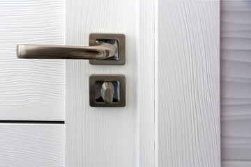 Door handle with lock. Furniture fittings. Close Up of a door handle on a white textured door.