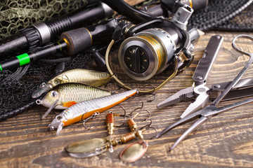 Fishing rods and spinnings in the composition with accessories for fishing on the old background on the table