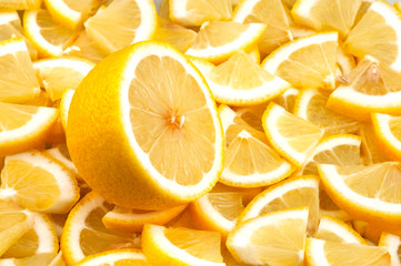 One cut lemon lies on a background of lemon slices.