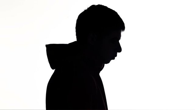 silhouette of a young man takes off the hood of a sweatshirt on white isolated background, concept fashion and casual style