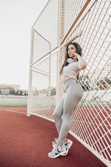 Fototapeta na wymiar Beautiful fitness woman in sportswear posing near grid.