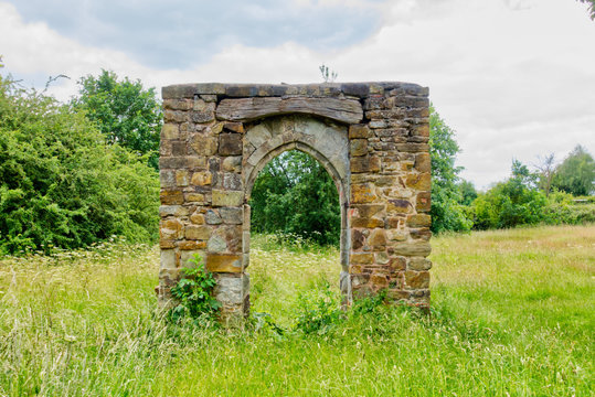 Ruined stone archway in grassy field