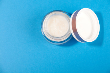white cosmetic cream in a jar on a blue background