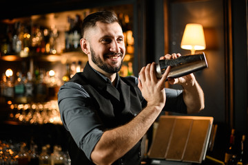 Male bartender shakes cocktail in stainless steel shaker