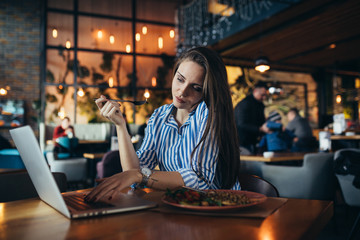 businesswoman having lunch and using laptop in restaurant