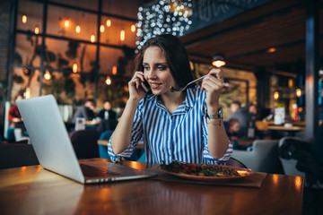 businesswoman having lunch and using laptop in restaurant