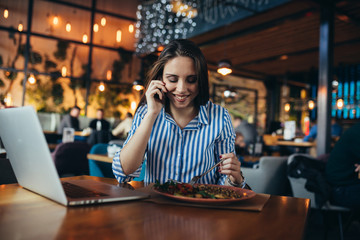 businesswoman having lunch and using laptop in restaurant