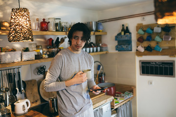 Fototapeta premium man drinking coffee using mobile phone in kitchen