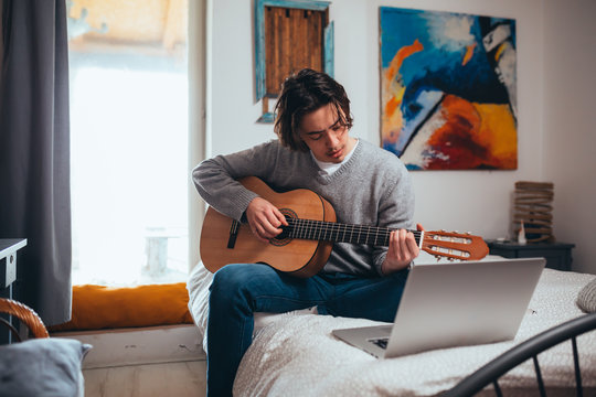 young man playing guitar in his room