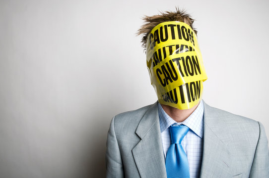 Unrecognizable office worker standing with his head wrapped in black and yellow caution tape
