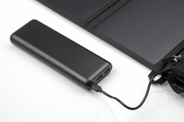 The solar panel charges the power bank battery for the smartphone on a white background. digital technologies and devices