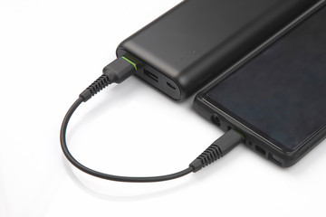 powerbank charges a smartphone battery on a white background. digital technologies and devices