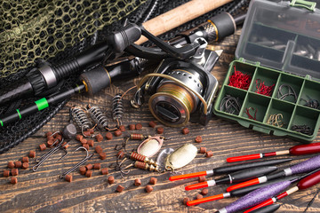 Fishing rods and spinnings in the composition with accessories for fishing on the old background on the table