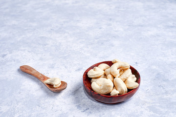 cashew nut in a wooden bowl whith wooden spoon on a blue and white background top view
