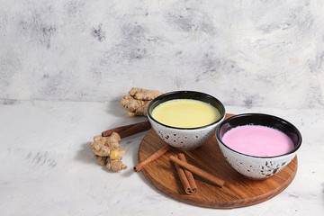 Turmeric latte and pink golden milk for a better sleep, ginger and cinnamon on a gray table, a fashionable relaxing drink, has antioxidant properties, helps detoxify the body, a place for text