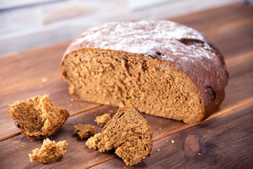 Traditional dark homemade bread sliced and broken into pieces, top view on a dark wooden table