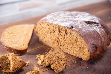 Traditional dark homemade bread sliced and broken into pieces, top view on a dark wooden table