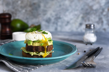 Toasted bread with salad, avocado and poached egg for breakfast. Horizontal focus.