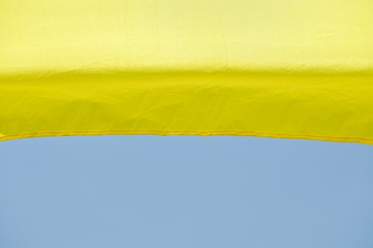 A Horizontal Strip Of Yellow Tarpaulin And A Strip Of Blue Sky.