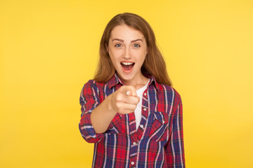 Hey you! Portrait of amazed ginger girl in checkered shirt happily indicating at camera and looking surprised wondered, pointing finger choosing you. indoor studio shot isolated on yellow background