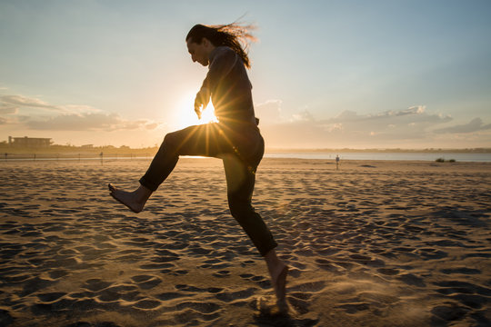 millennial guy running and dancing on beach during sunset