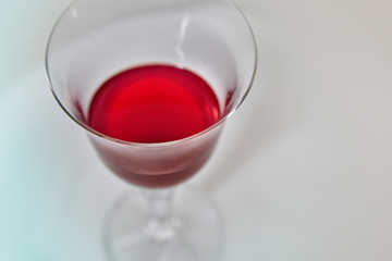 A glass of red wine on a light background, top view