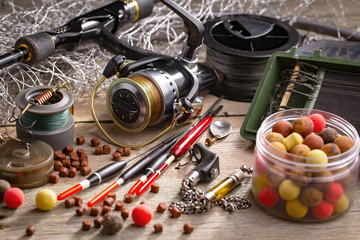 Fototapeta na wymiar Fishing rods and spinnings in the composition with accessories for fishing on the old background on the table