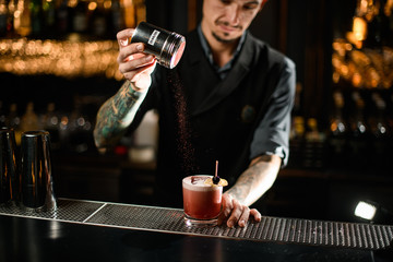 Male bartender prepares alcohol drink with raspberry powder