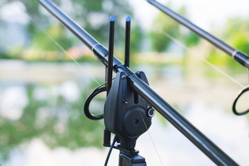 Professional carp fishing bite alarm, close-up from lakeside background.