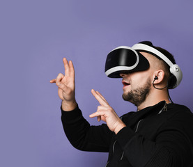 Young bearded man wearing virtual reality glasses pointing fingers up. Smartphone using with VR goggles