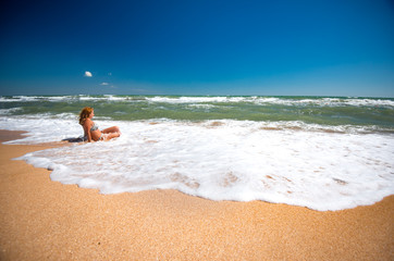 The girl lies in the waves and enjoys the view of the beautiful sea.