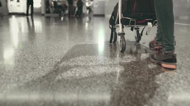 Woman Step with Luggage Cart at Airport Terminal. Tracking Shot of Female Legs in Trainers. Passenger Pushing Trolley with Backpack to Boarding Gate. Journey Time. Footage Shot in 4K