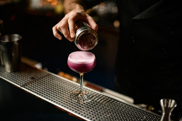 Close-up of male bartender sprinkling alcohol cocktail