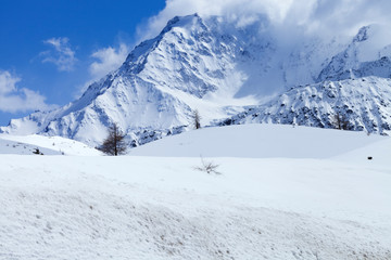 Fototapeta na wymiar Snowy mountain covered with clouds, winter landscape in Swiss Alps .