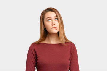 Portrait girl confused frightened look bite lip. Beautiful young woman wears Burgundy-colored jacket sleeves isolated on white background in Studio with an empty space for text and advertising.