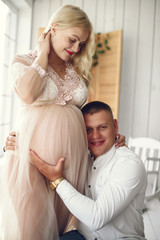 Pregnant woman. Blonde in a long pik dress. Man in a white shirt