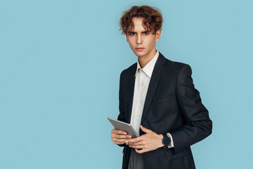 Freestyle. Young businessman in suit standing isolated on gray with digital tablet thoughtful copy space