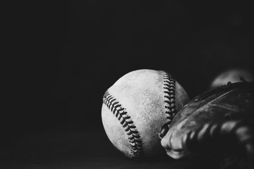 Close up of old baseball with glove, copy space on black background.