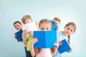 Cute little children with books on color background