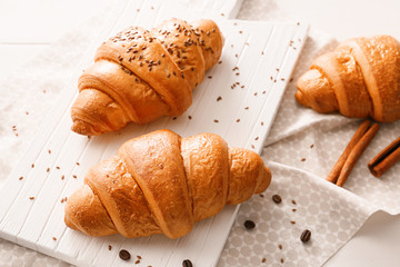 Board with tasty croissants on table