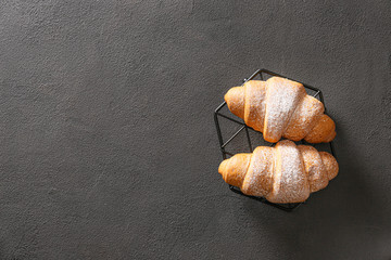 Grid with tasty croissants on dark background