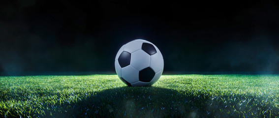 Football on an illuminated empty sports field at night
