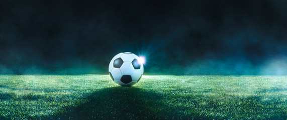 Football on an illuminated empty sports field at night