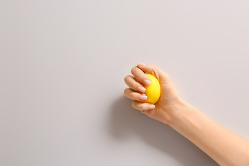 Hand squeezing stress ball on light background - obrazy, fototapety, plakaty