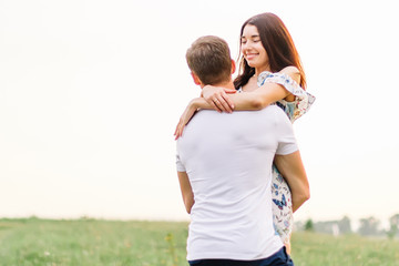 Young couple in love hugging on grass field. Walking along grass field.