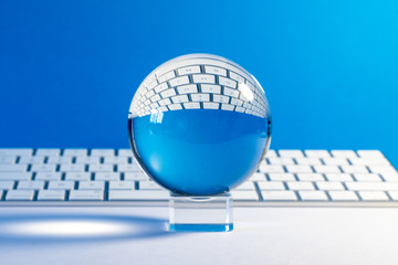 Boule de cristal placée devant un clavier d'ordinateur sur fond bleu