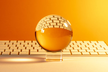 Boule de cristal placée devant un clavier d'ordinateur sur fond orange