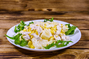 Festive salad with chicken breast, canned pineapple, cheese, sweet corn and mayonnaise on wooden table